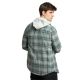 Camisa de manga larga con cuello y botones, con un patrón de cuadros en tonos azules, verdes y marrones. La camisa se lleva abierta sobre una remera con capucha de color claro.