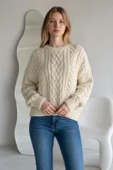 Sweater de punto grueso color rojo, con diseño de trenzas verticales, cuello redondo y puños acanalados.
