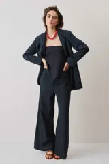 Pantalón de lino negro de corte holgado y pierna ancha, con bolsillos laterales y cierre frontal.