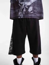 Bermuda de tela deportiva fina, color negro, con pretina elástica, parche bordado y detalles de encaje en los laterales.
