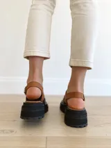 Sandalias de cuero color negro y camel, con plataforma track y hebilla ajustable.