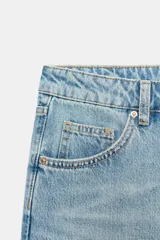Jeans de tiro medio con diseño de cinco bolsillos, cierre frontal con cremallera y botón, en tono celeste con efecto deslavado.
