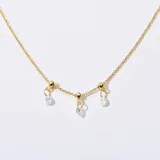 Gargantilla dorada con cadena fina y tres dijes colgantes: dos con forma de esfera y uno con forma de lágrima con incrustaciones de cristal.