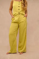 Pantalon de vestir color lima con finas rayas verticales blancas, de corte sastrero y piernas anchas, con bolsillos laterales y trabillas para cinturon.