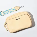 Bandolera color amarillo con correa de tela estampada y cierre metálico.