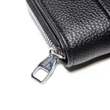 Billetera de tamaño compacto en color negro, confeccionada en material símil cuero con textura granulada. Presenta un diseño con costuras verticales decorativas y el logo de la marca en metal plateado en la parte frontal.