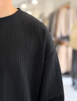 Buzo oversize marrón de manga larga, confeccionado en tela texturada con líneas verticales, cuello redondo y calce holgado.