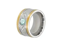 Anillo de acero plateado con rebordes dorados y cristal celeste facetado en forma de corazón.