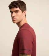 Remera deportiva de hombre con tecnología dry fit, cuello redondo y manga corta. Presenta un diseño liso en color beige con una pequeña etiqueta decorativa en el dobladillo.