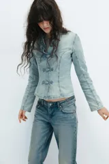 Camisa de denim celeste con cuello solapa, manga larga y cierre frontal con nudos de tela.