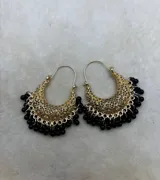 Aros tipo argolla dorados con diseño calado de filigrana y colgantes de pequeñas cuentas rojas en el borde inferior.