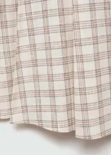 Falda midi de tiro alto con estampado de cuadros en tonos neutros. Presenta cierre lateral con cremallera, diseño evasé y costuras decorativas. Confeccionada en tejido ligero de algodón.