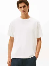Remera de punto de algodón moteado, color blanco, con cuello redondo y escudo con monograma TH bordado en tono sobre tono en el pecho. Presenta un corte amplio y cómodo.