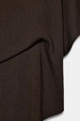 Top tipo capa blanco de punto fluido, con mezcla de viscosa, cuello bote, mangas cortas y bajo asimétrico.