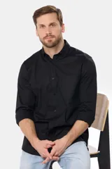 Camisa de vestir manga larga color negro, con cuello abotonado (button-down), bolsillo frontal con logo bordado a tono y cierre de botones.