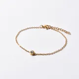 Pulsera dorada con cadena de eslabones finos y dije de cristal engarzado.