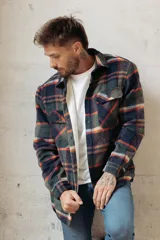 Sobrecamisa de corte holgado con diseño a cuadros en tonos azul marino y marrón, confeccionada con forro interior de corderito sintético, cuello clásico, cierre frontal de botones y bolsillos en el pecho.