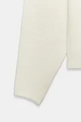 Jersey de punto rib color blanco, con cuello barco y mangas largas con sisas anchas.