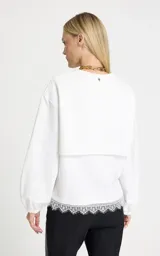 Buzo de tejido de punto color blanco, con cuello redondo acanalado, hombros caídos y mangas largas con puños elásticos.