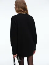 Sweater de tejido de punto acanalado en color blanco, con cuello redondo, mangas largas y corte holgado. Presenta un diseño minimalista y contemporáneo.