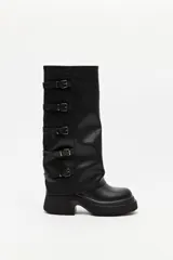 Bota de caña alta estilo biker, color negro, con plataforma robusta y suela dentada. Presenta múltiples tiras laterales con hebillas metálicas ajustables.