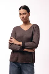 Buzo de tejido suave y liviano en color chocolate, con escote en V y mangas largas. Presenta un detalle de estampado animal print en el interior de los puños, visible al doblarlos.