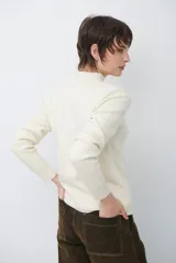 Polera de tejido de punto fino en color beige, con cuello alto y mangas largas con puños acanalados.
