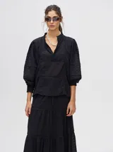 Camisa de broderie de algodón color negro, con diseño de calados, cuello mao con cierre de botones, mangas abullonadas con puños fruncidos y detalles de galones con transparencias.