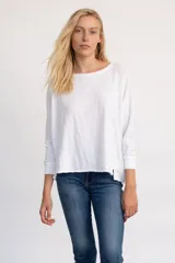 Remera de algodón de tejido liviano, con escote redondo amplio, mangas largas y silueta relajada. Presenta terminaciones desflecadas en el cuello y el ruedo, con un diseño de caída fluida.