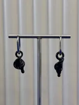 Aros colgantes compuestos por una argolla de acero quirúrgico y un dije de cristal de Murano negro con forma de flor cala.