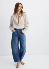 Jeans de denim azul de corte wide leg y tiro medio, con diseño clásico de cinco bolsillos y cierre frontal con botón y cremallera.