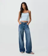 Pantalón wide de jean azul con tiro bajo, piernas amplias, bolsillos delanteros y traseros, y cierre tradicional con botón y cremallera.