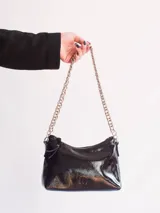 Cartera tipo media luna de cuero natural color marrón, con cierre superior y correa de cadena metálica plateada. Presenta el logo de la marca grabado en el frente.