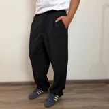 Pantalón sastrero negro de corte baggy, con pliegues en la parte delantera y bolsillos laterales.