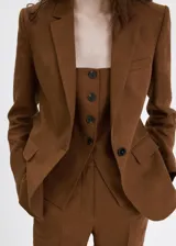 Blazer de lino color marrón, de diseño recto, con cuello pico con solapa, manga larga y cierre de un botón en la parte delantera.