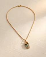 Collar de bronce dorado con cadena de eslabones finos y dije colgante en forma de zapatito decorado con esmalte negro, turquesa, blanco y detalles brillantes.