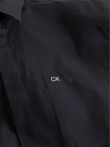 Camisa negra de manga corta con corte boxy, cuello en punta, bolsillo de parche en el pecho y logo CK bordado.