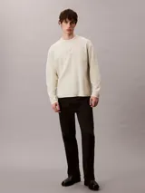 Sweater de punto color beige con cuello redondo, mangas largas y corte regular. Cuenta con el logo distintivo de Calvin Klein bordado en relieve al tono en el pecho.