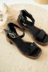 Sandalias de cuero color beige con plataforma y taco cuadrado de madera. Presentan una tira frontal ancha y una tira ajustable en el tobillo con hebilla metálica plateada.