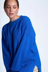 Sweater azul eléctrico de punto acanalado, con cuello redondo y mangas largas. Corte holgado con aberturas laterales.