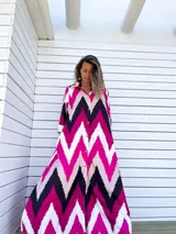 Vestido camisero largo con diseño de estampado chevron en colores fucsia, beige y negro. Presenta cuello camisero, cierre frontal con botones y mangas tres cuartos.