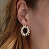 Aros dorados con forma de sol, con incrustaciones de cristales blancos.