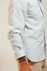 Camisa de vestir blanca de manga larga con cuello abotonado y cierre frontal de botones.