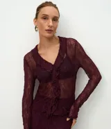 Blusa de encaje transparente color bordó, con mangas largas, escote en V con volados frontales y bajo fruncido.
