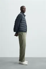 Chaleco acolchado verde oscuro, con cuello alto, cierre frontal con cremallera y bolsillos laterales. Confeccionado en tejido técnico repelente al agua.