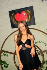 Vestido corto negro con diseño cut-out en la cintura y detalle de encaje en el centro del busto. Presenta breteles finos, falda con volado en el ruedo y flecos decorativos.