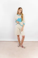 Buzo de lana tejido a mano, de color crudo con diseño de corazón grande en el centro, cuello redondo, puños y ruedo en color celeste.