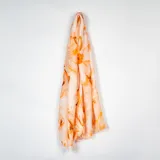 Pashmina de tela ligera con estampado abstracto en tonos naranja y crema, con bordes desflecados.