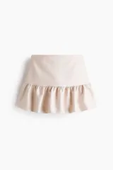 Short pollera de tiro medio con diseño de volado en el ruedo y cierre lateral oculto.