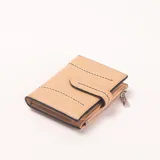 Billetera color beige con detalles de costuras decorativas en blanco. Cuenta con cierre de broche y un bolsillo exterior con cierre.